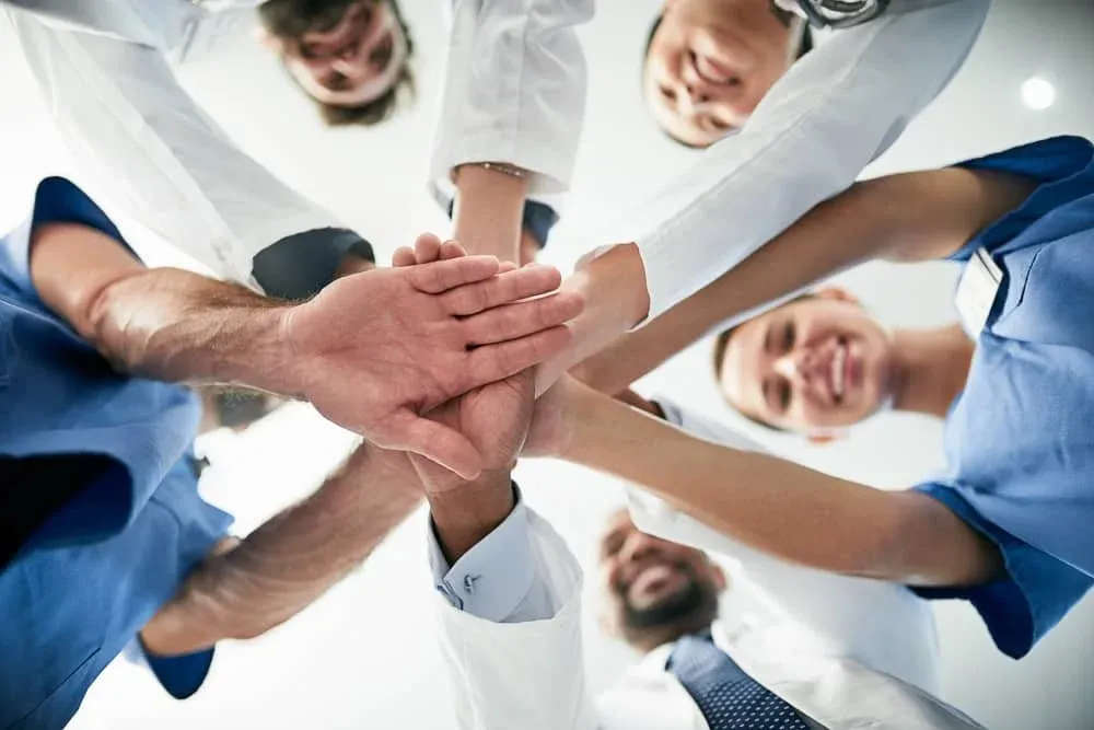 Equipo de profesionales de la salud uniendo sus manos al centro en señal de trabajo en equipo