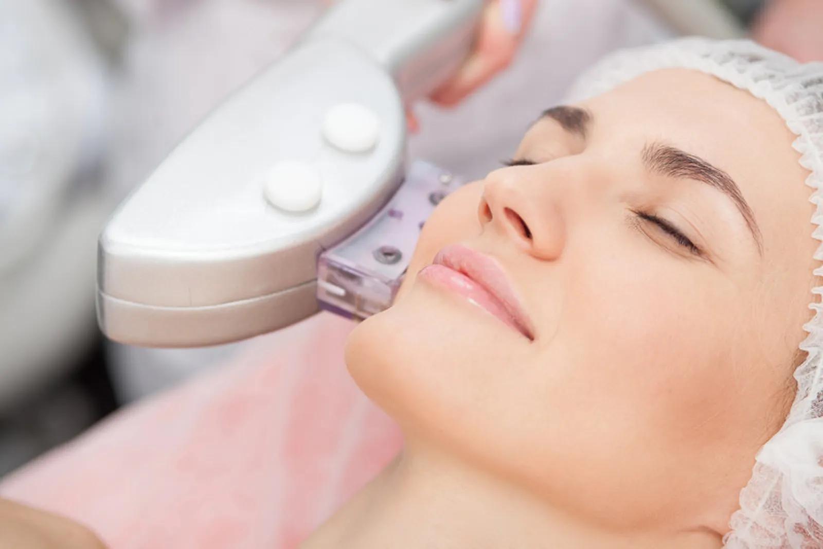 Paciente recostada con gorro protector durante un tratamiento de láser facial